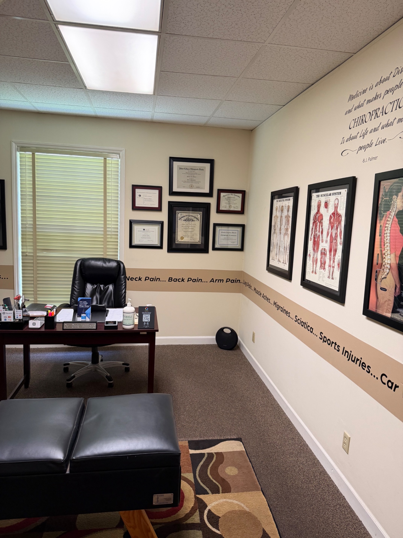 Dr. Willard’s desk with framed diplomas and anatomy posters