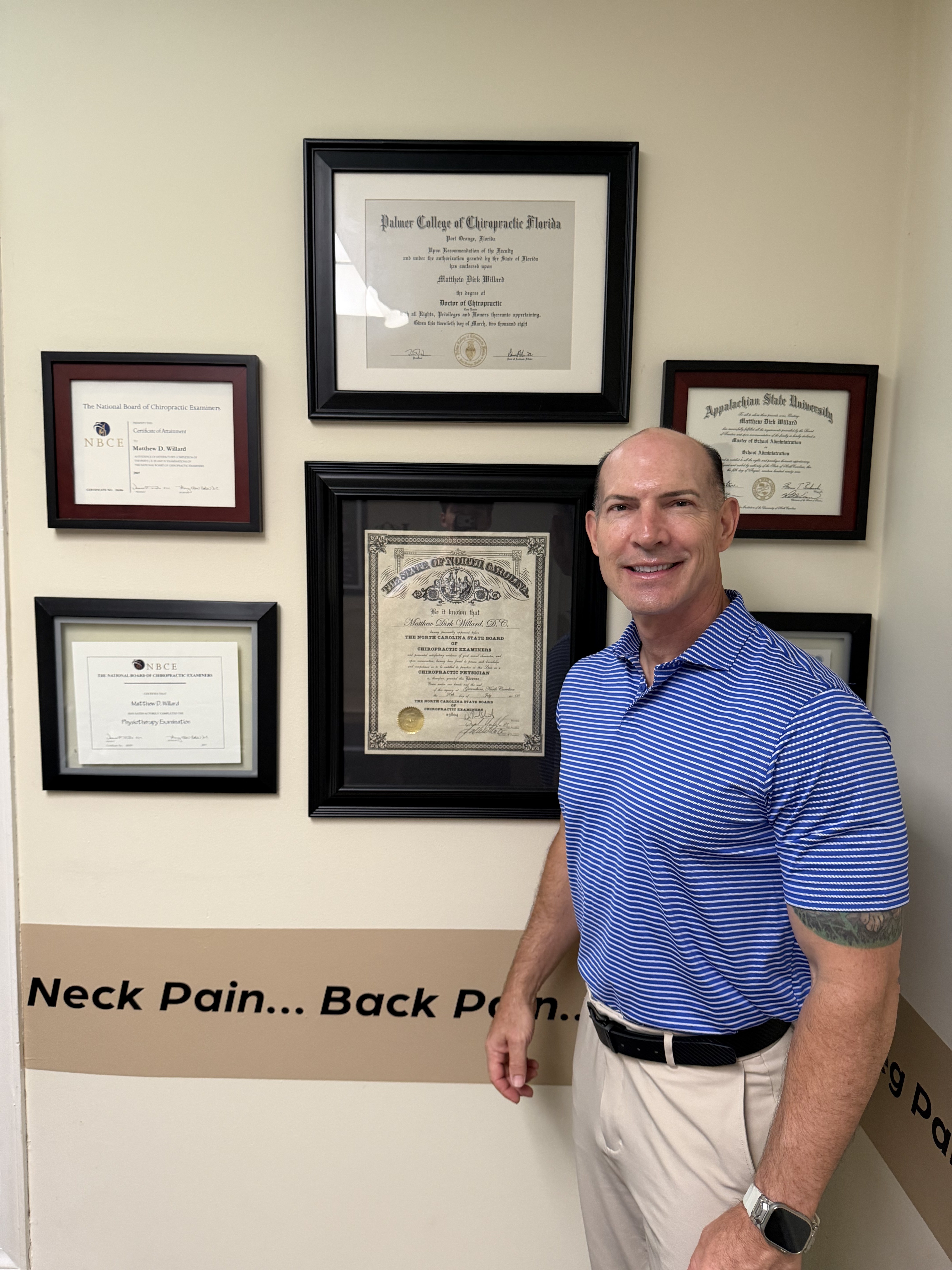 Dr. Dirk Willard in front of his chiropractic licenses and diplomas